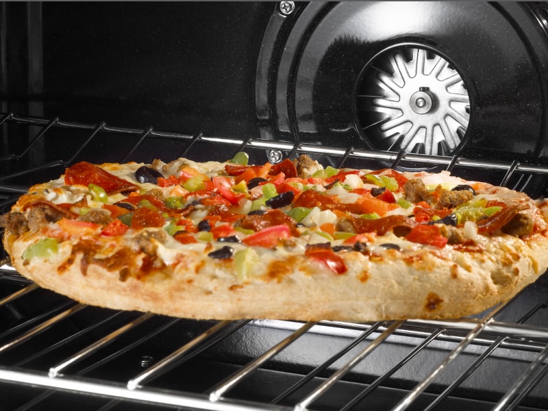 A flatbread pizza cooking in an oven A flatbread pizza cooking in an oven