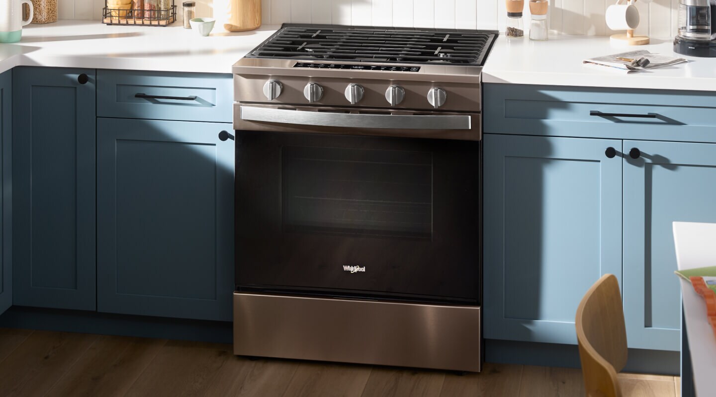 A Whirlpool® Slide-In Gas Range against bright blue kitchen cabinets