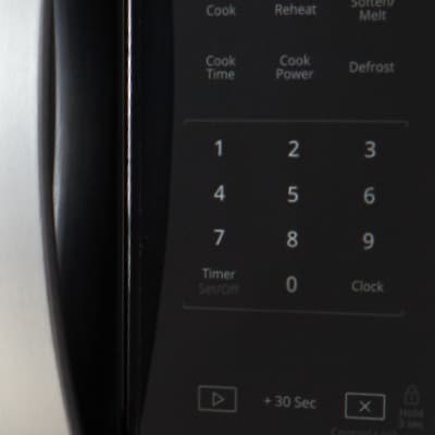 Closeup of a person using touch controls on a microwave