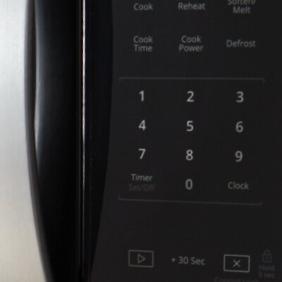 Closeup of a person using touch controls on a microwave
