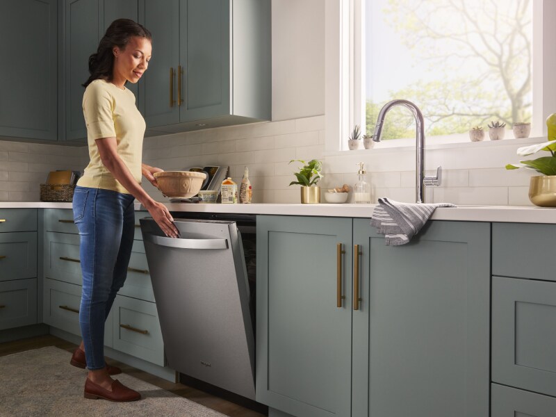Person opening a stainless steel dishwasher Person opening a stainless steel dishwasher