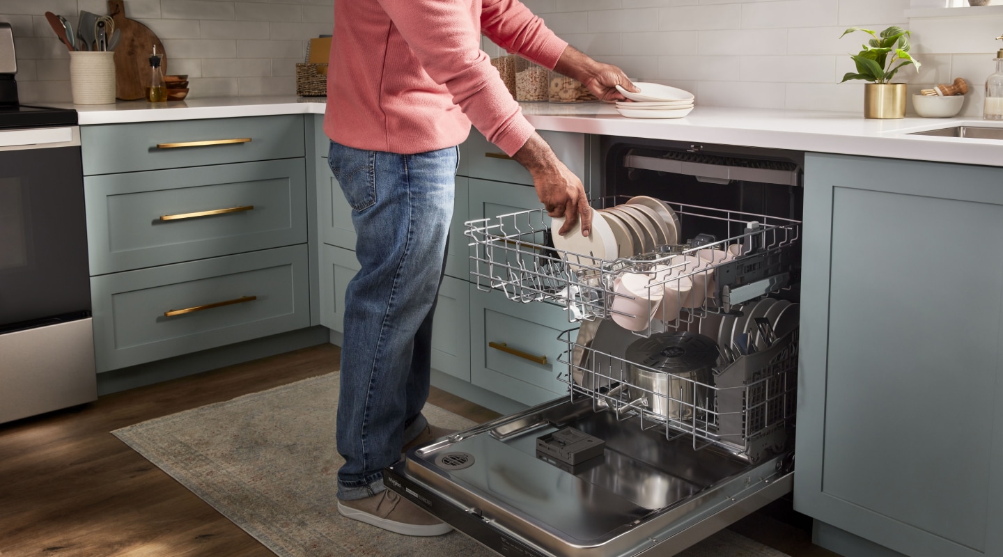 Person loading dishes into a dishwasher Person loading dishes into a dishwasher