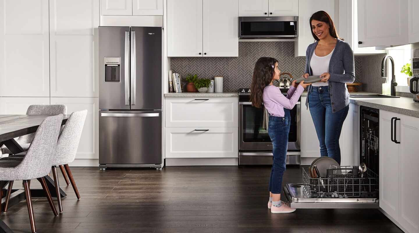 Person handing a child a clean dish in a kitchen Person handing a child a clean dish in a kitchen