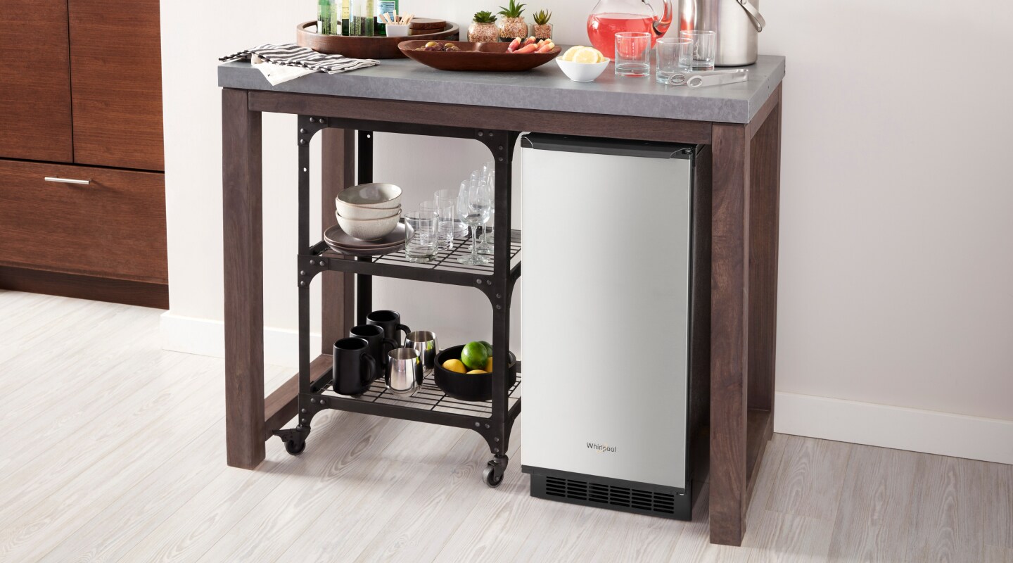 An undercounter ice maker beneath a counter with beverages placed on it