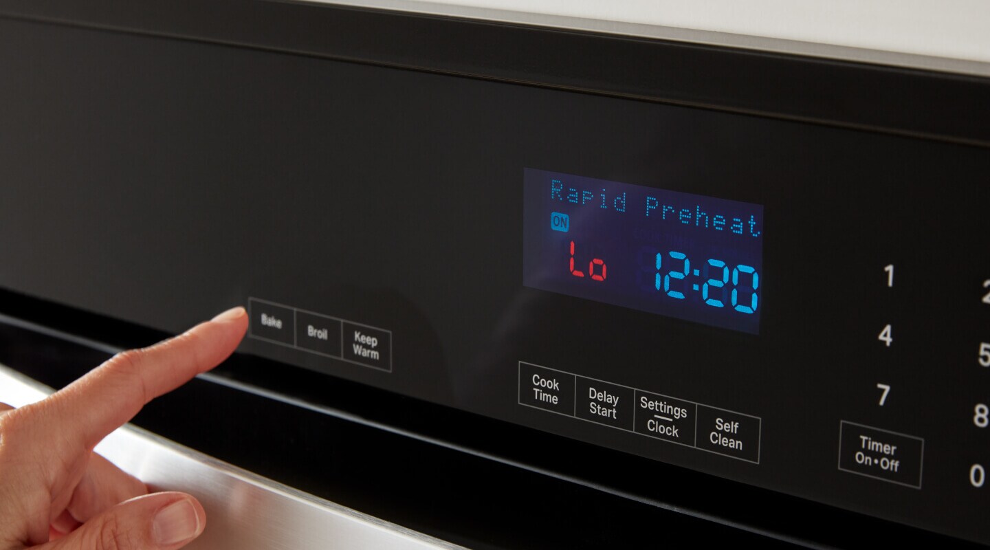 A finger pushing a button on the display of an oven