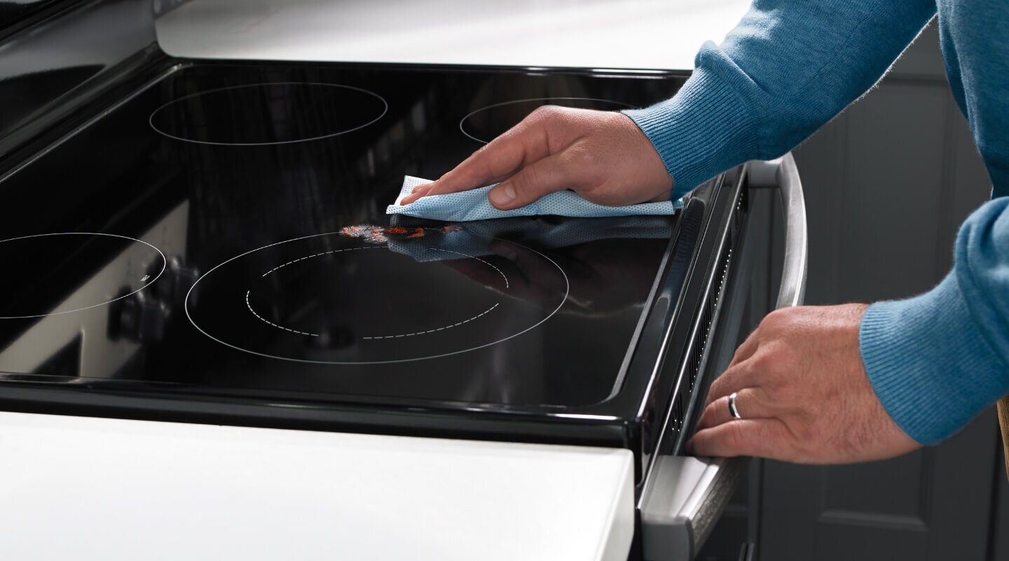 A hand wiping the cooking surface of an electric range
