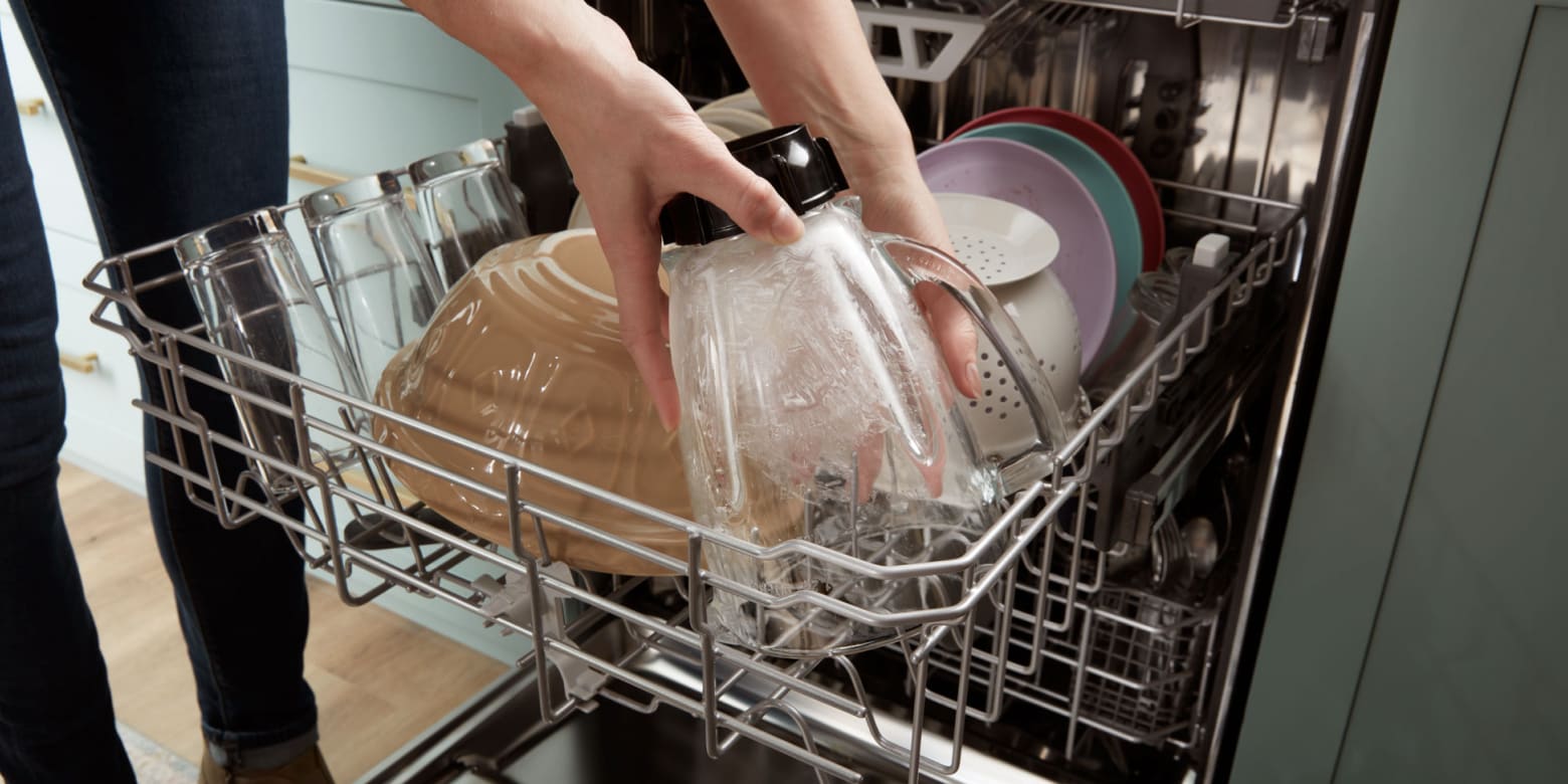 Person placing glass blender jar in top rack of dishwasher Person placing glass blender jar in top rack of dishwasher