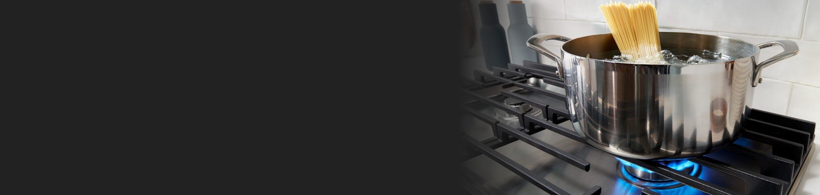 A pot resting on gas stove burner grates.