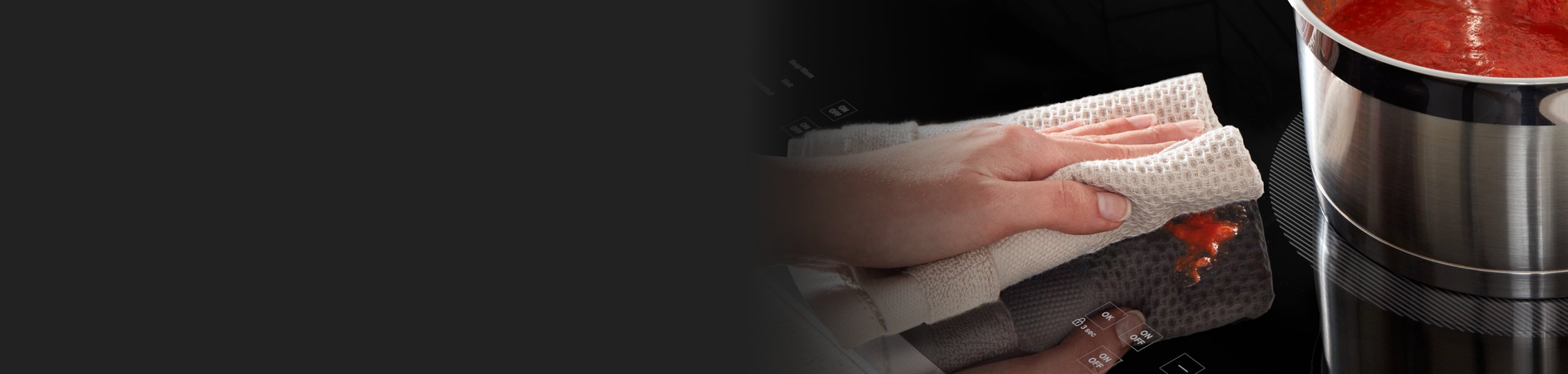 Person cleaning a Whirlpool® induction cooktop with a towel.