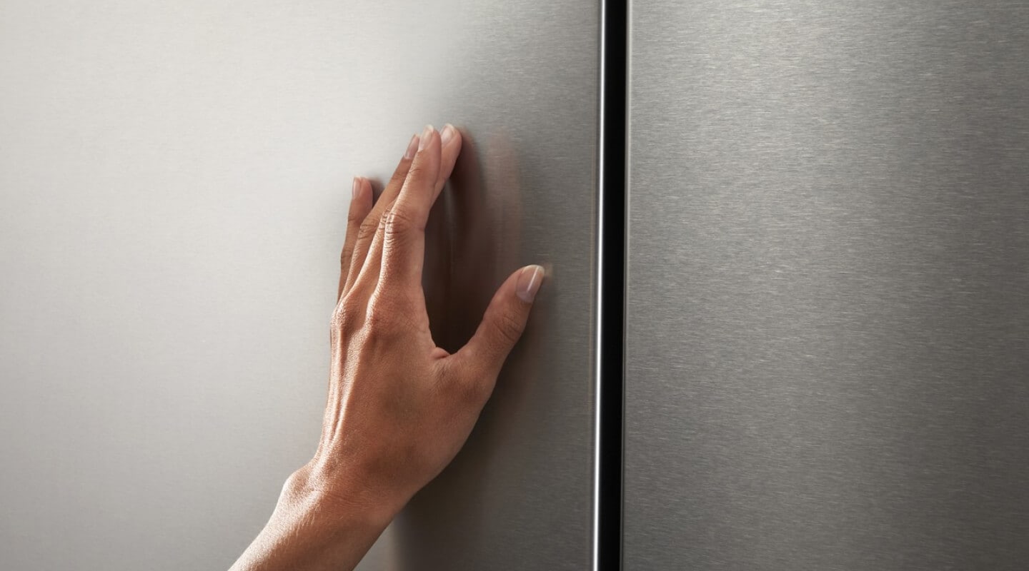 Hand touching a large stainless steel kitchen appliance