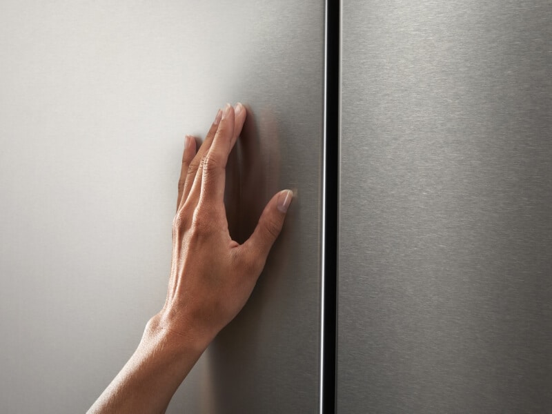 Hand touching a large stainless steel kitchen appliance