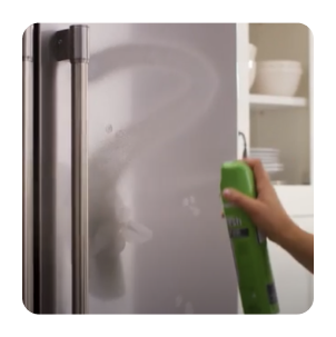Hand spraying affresh® stainless steel cleaner onto refrigerator