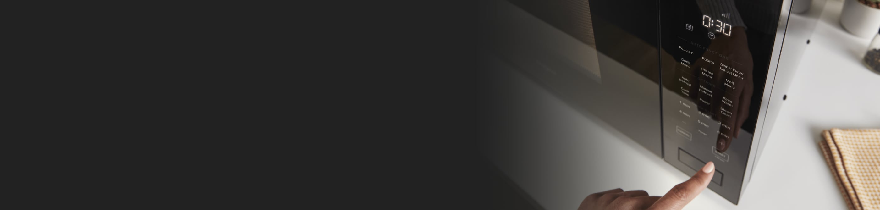 Close up of a person pressing buttons on a black microwave