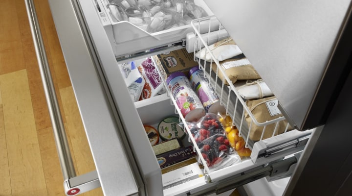 Shelves of food and an ice bin inside of a freezer Shelves of food and an ice bin inside of a freezer