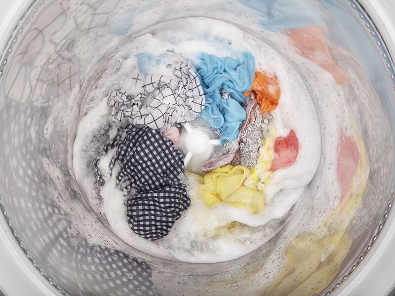 Top view of a washer agitating clothes in a soapy drum Top view of a washer agitating clothes in a soapy drum