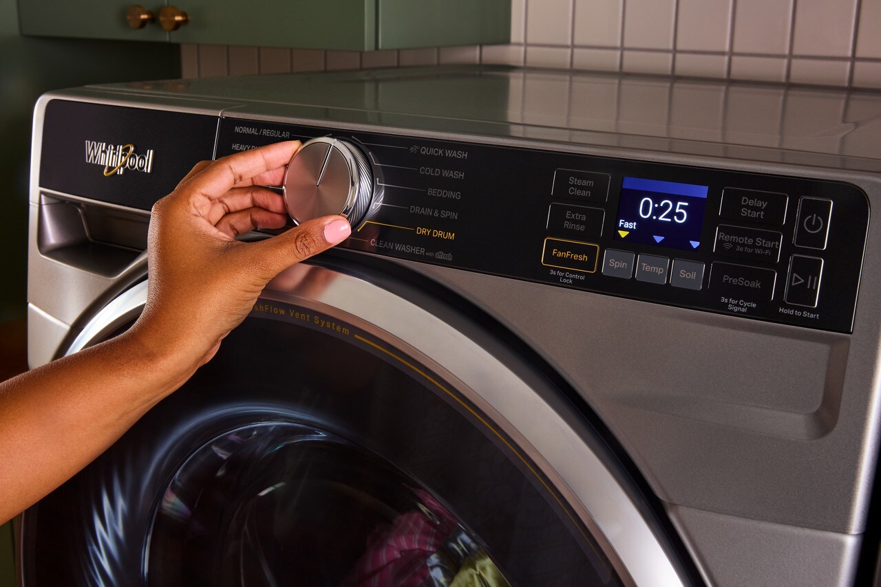 A hand turning the cycle knob on a Whirlpool® Front Load Washer