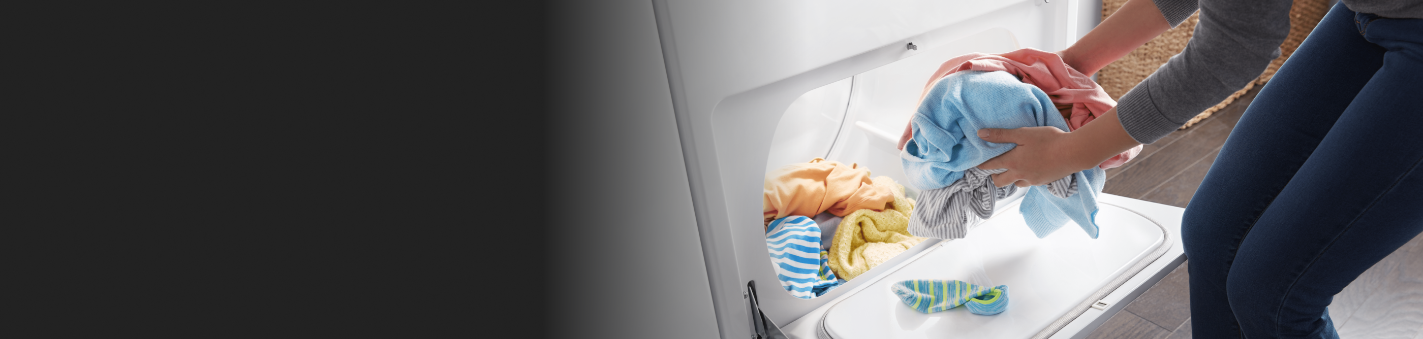 A person taking colorful clothes out of a dryer.