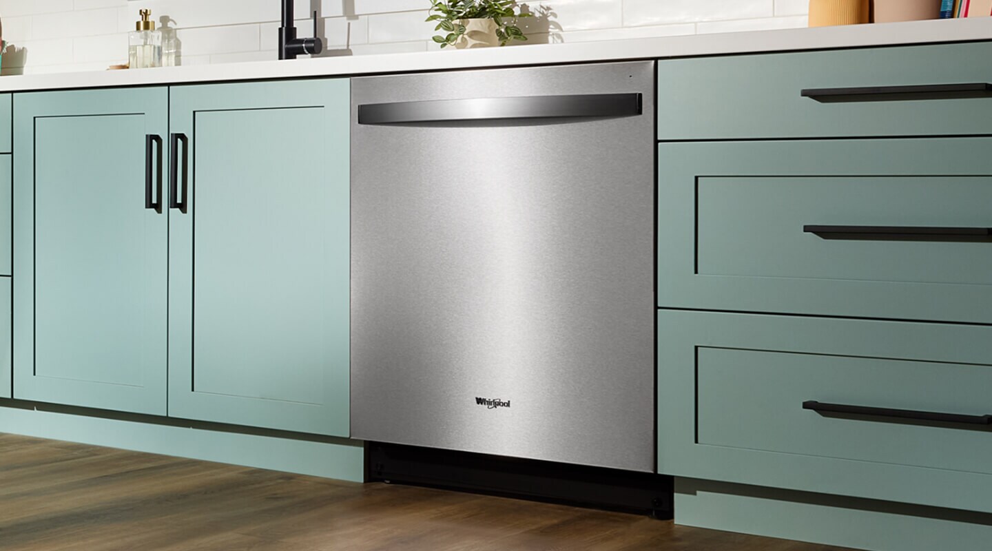 A Whirlpool® Top Control Dishwasher in a kitchen with light green cabinetry
