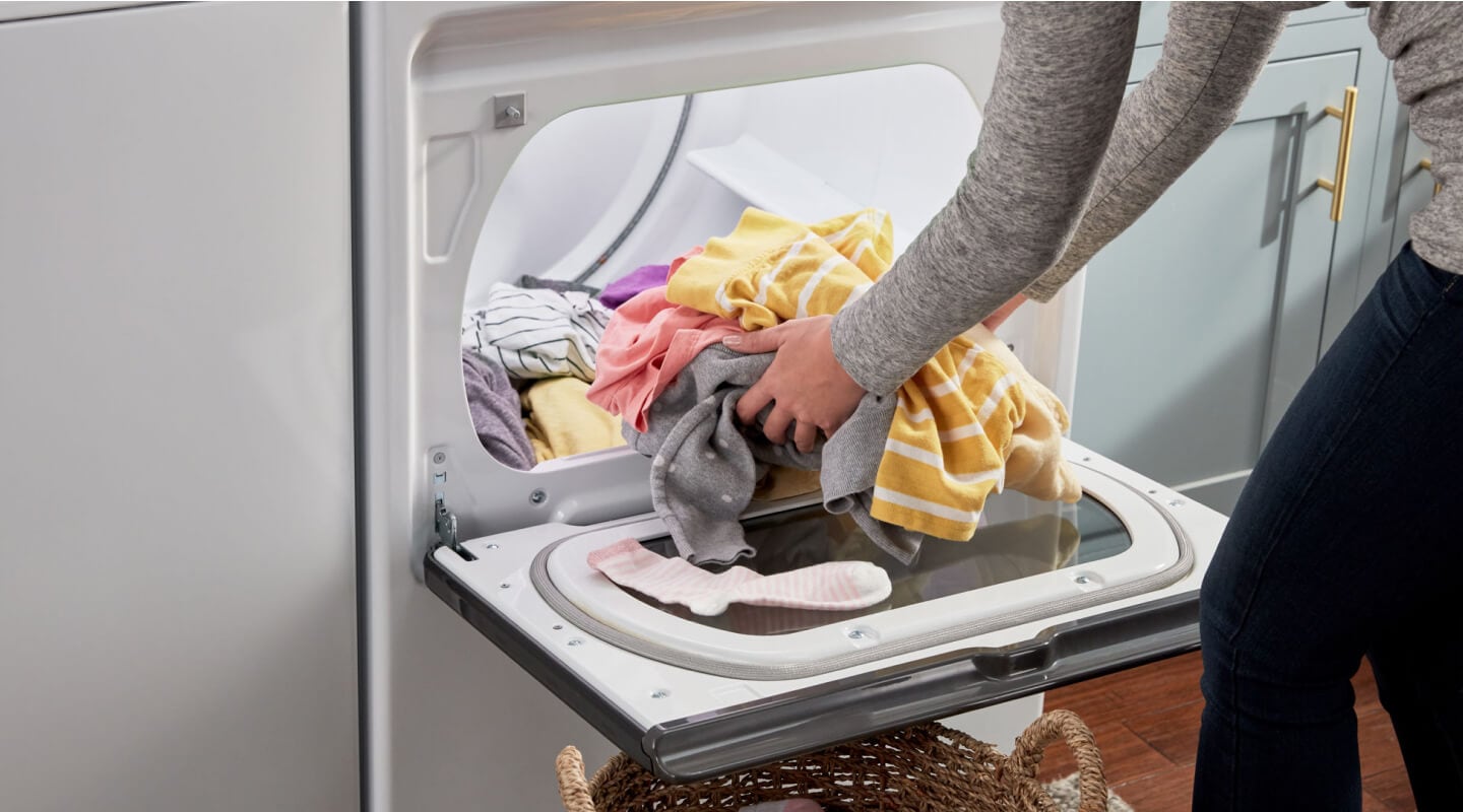 A person unloading laundry from a dryer A person unloading laundry from a dryer