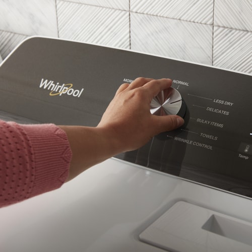 Hand selecting a cycle setting on a Whirlpool® dryer