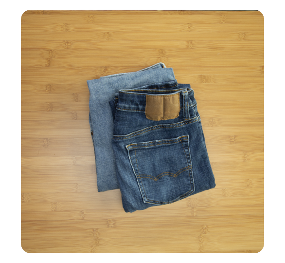 Two pairs of completely folded pants on a table Two pairs of completely folded pants on a table