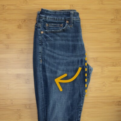 A pair of jeans folded in half with arrows instructing readers to tuck in the crotch portion