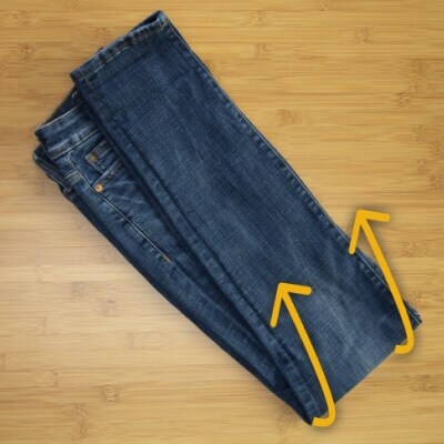 A pair of jeans with arrows instructing readers to fold the pants in half lengthwise