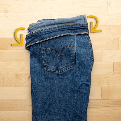 Jeans folded in half, lengthwise, with the waistband folded over