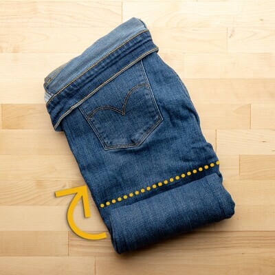 Arrows on jeans instructing readers to roll jeans upward toward folded-over waistband