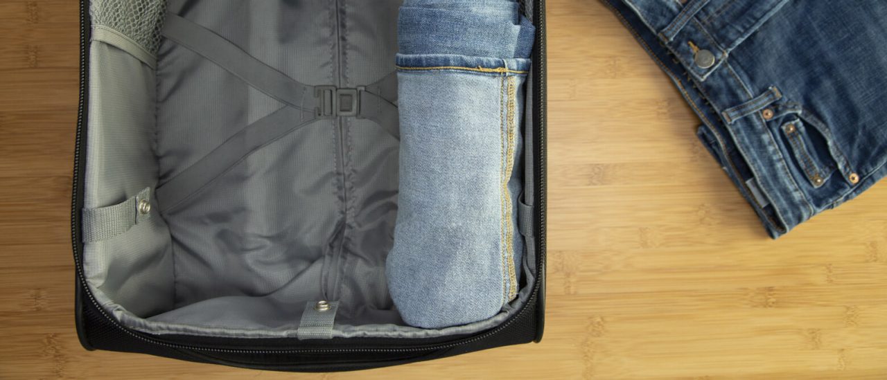 Open suitcase with folded pair of pants in it Open suitcase with folded pair of pants in it
