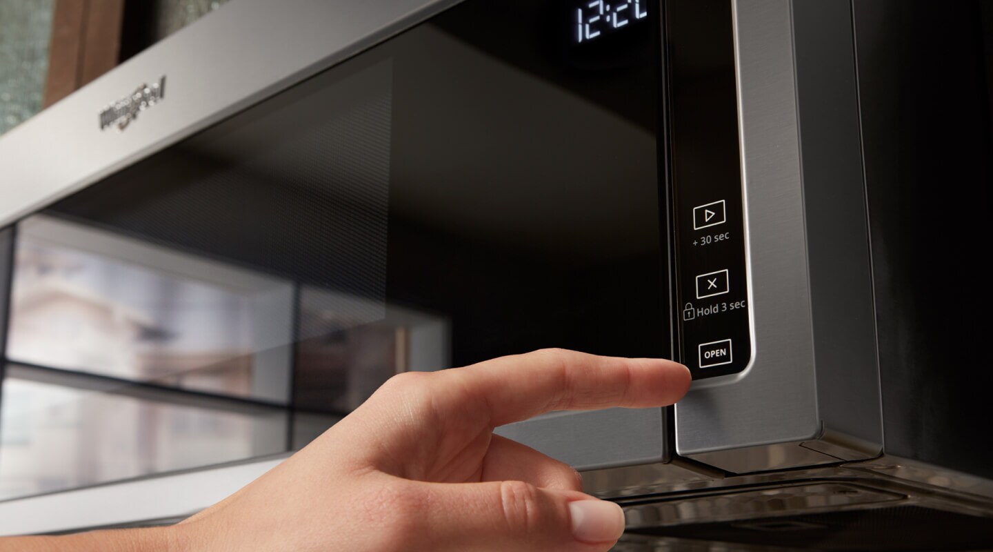 Person pressing a button on the microwave Person pressing a button on the microwave