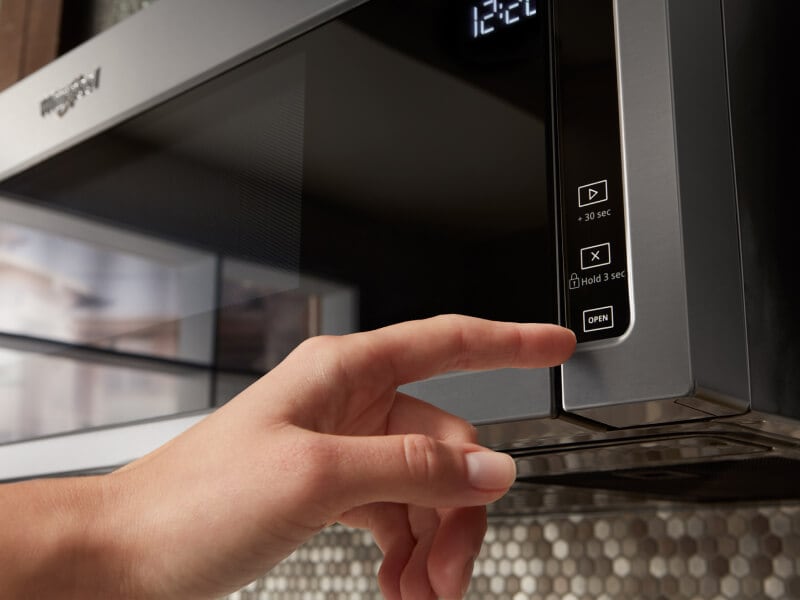 Person pressing a button on the microwave Person pressing a button on the microwave