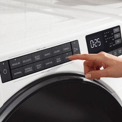 Person selecting settings on front load washer
