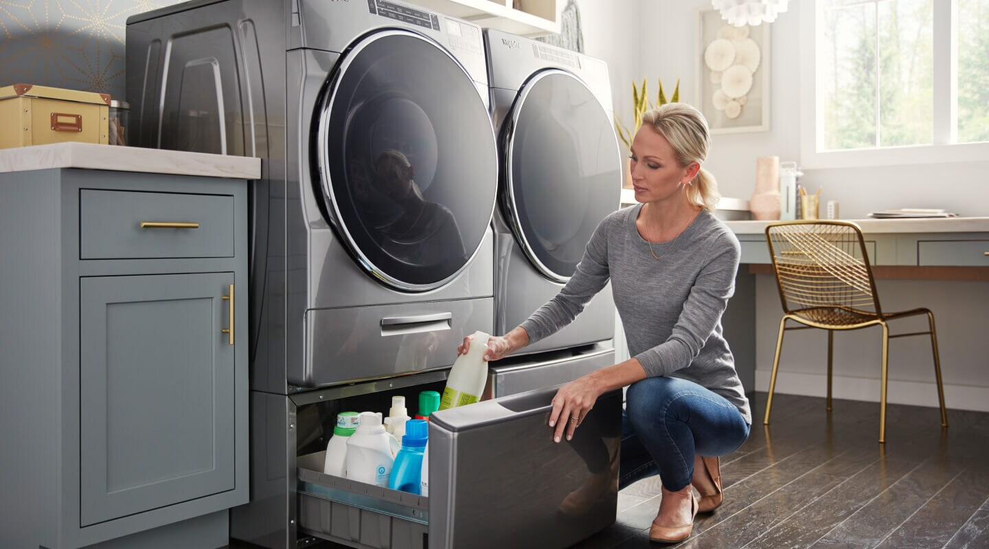 Person putting laundry supplies into the storage under the washing machine