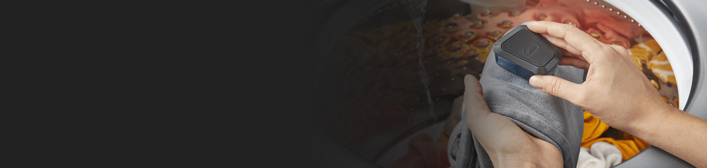 Person rubbing stain on denim over open washing machine