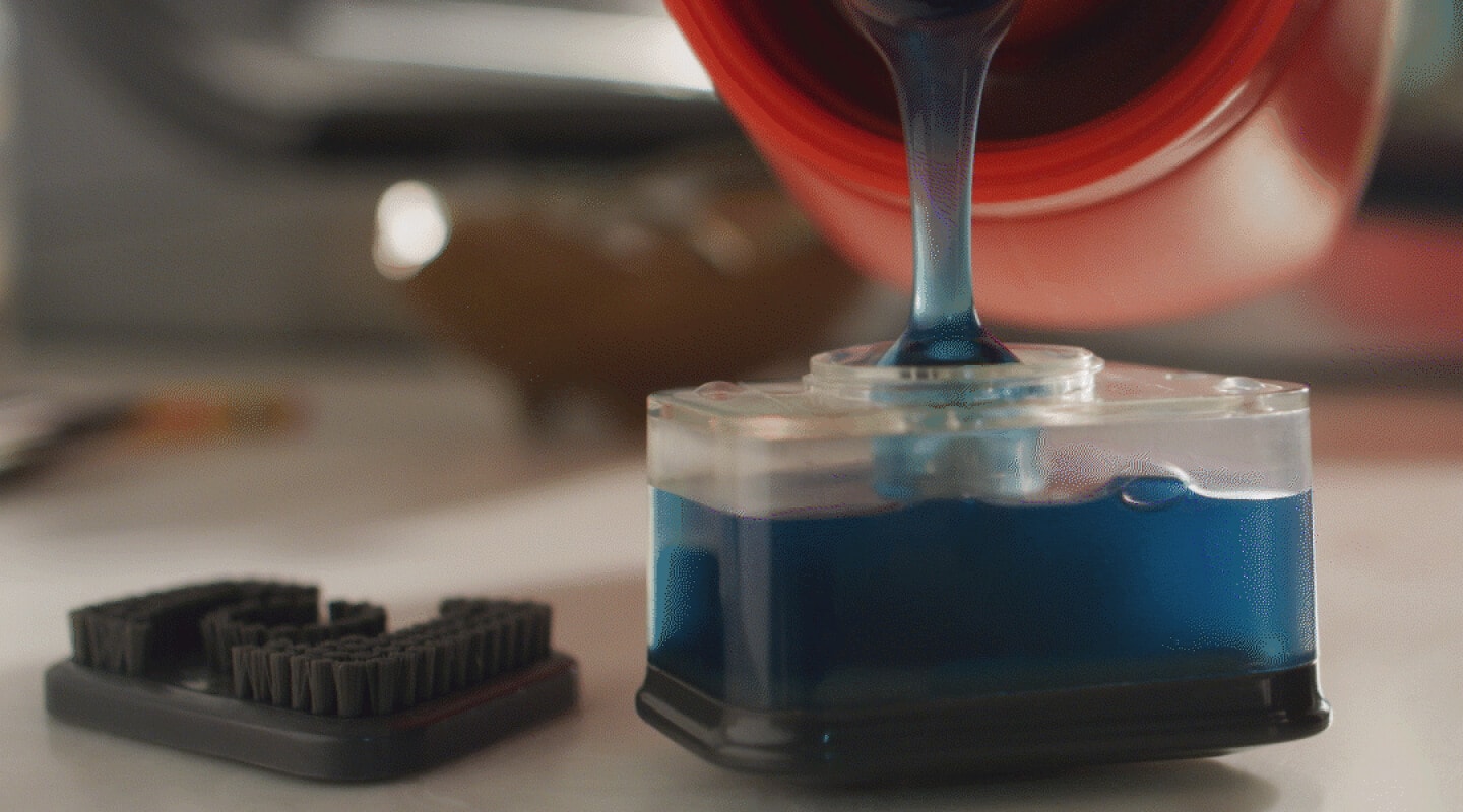 Person filling a stain spot treater with detergent Person filling a stain spot treater with detergent