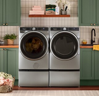 A Whirlpool®. Washer and Dryer set surrounded by green cabinetry