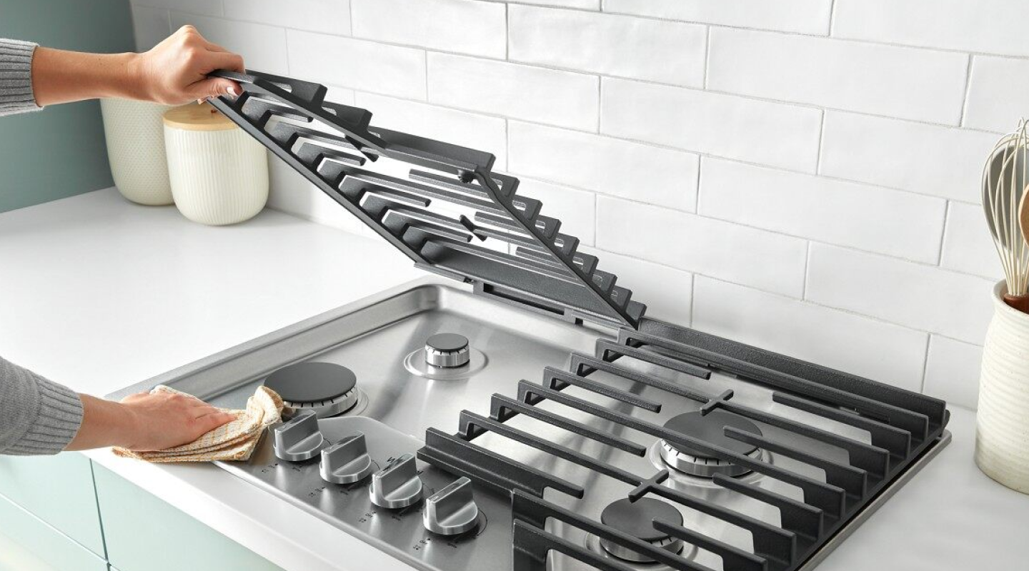 Hand lifting a grate on a gas cooktop