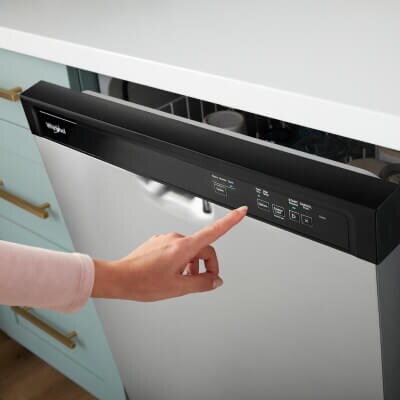 A person selecting an option on a dishwasher control panel
