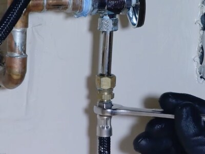 A person tightening a water valve