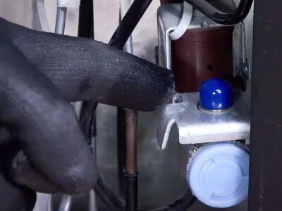 A person connecting the water supply tubing to the refrigerator