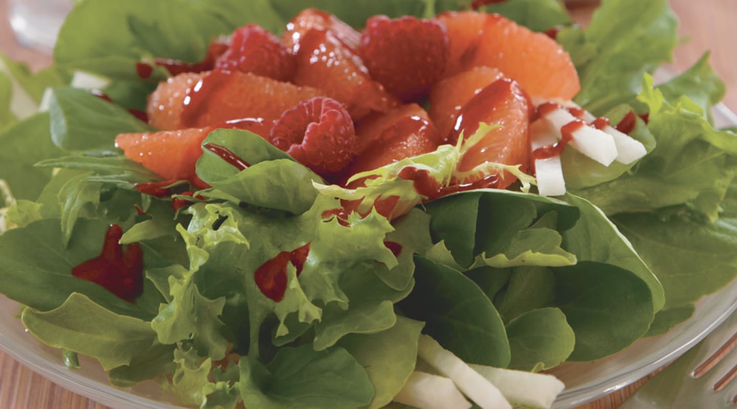 A salad topped with fresh fruit A salad topped with fresh fruit