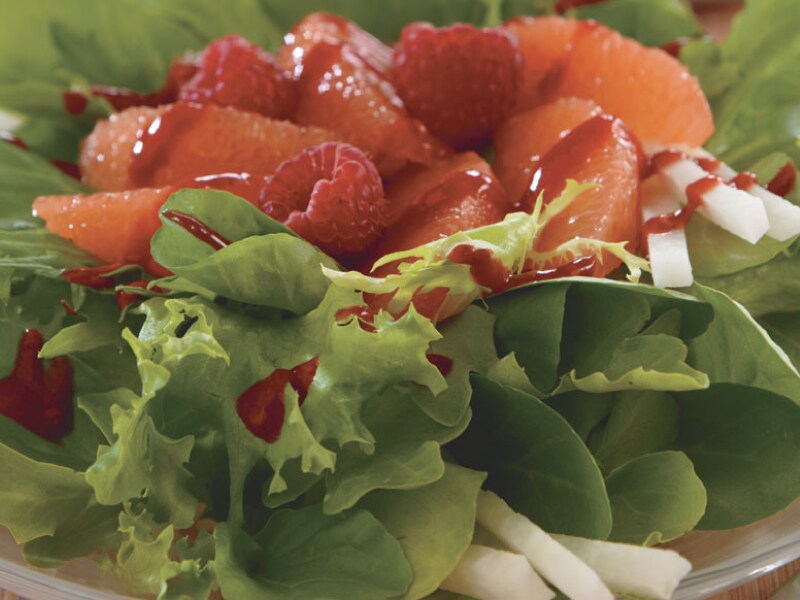 A salad topped with fresh fruit A salad topped with fresh fruit