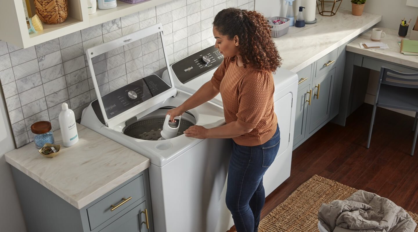 A person removing an agitator from a Whirlpool® Washing Machine