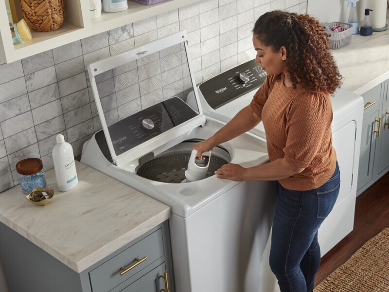 A person removing an agitator from a Whirlpool® Washing Machine
