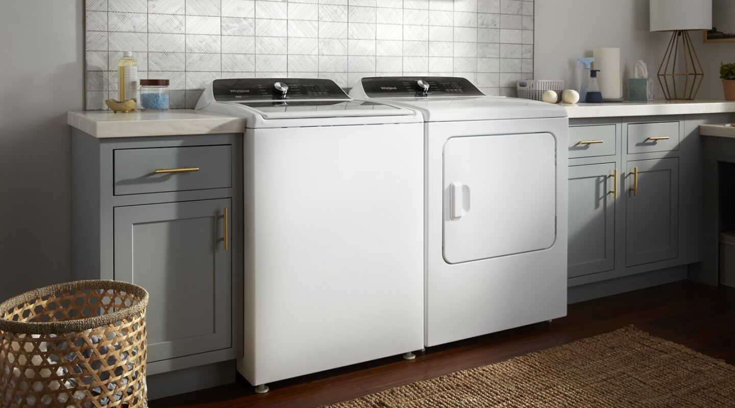 A side-by-side Whirlpool® Washer and Dryer set in a laundry room with light cabinets