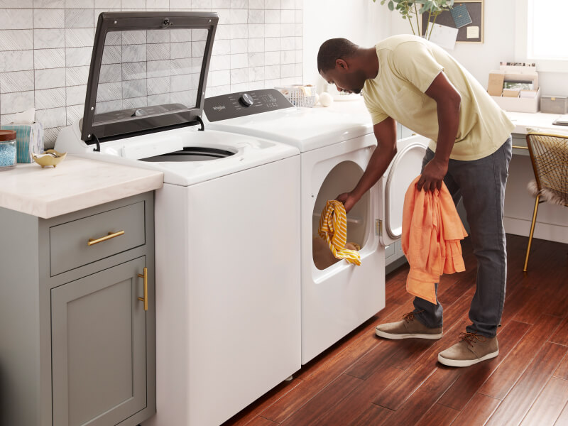 A man takes laundry out of a dryer A man takes laundry out of a dryer