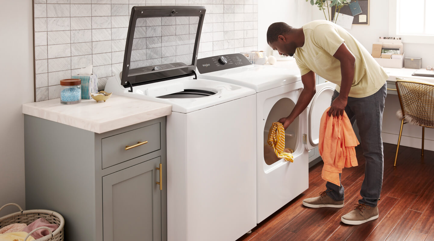A man takes laundry out of a dryer A man takes laundry out of a dryer