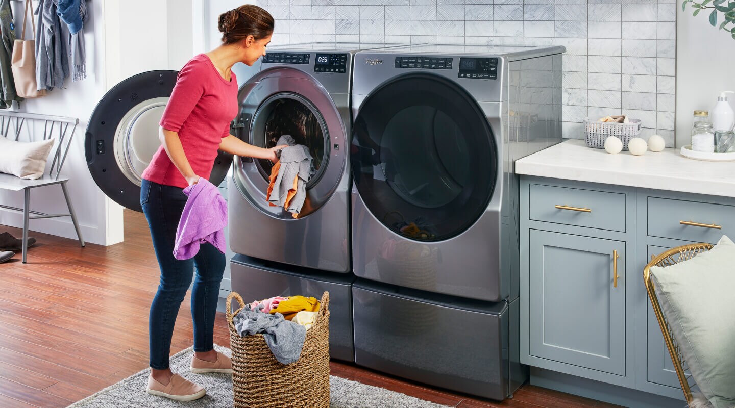 A woman puts laundry in a front load Whirlpool® Washer