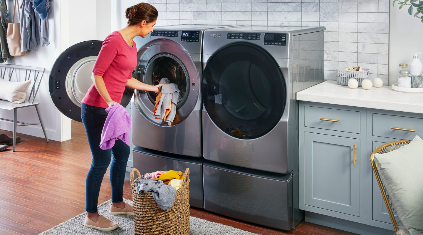 A woman puts laundry in a front load Whirlpool® Washer